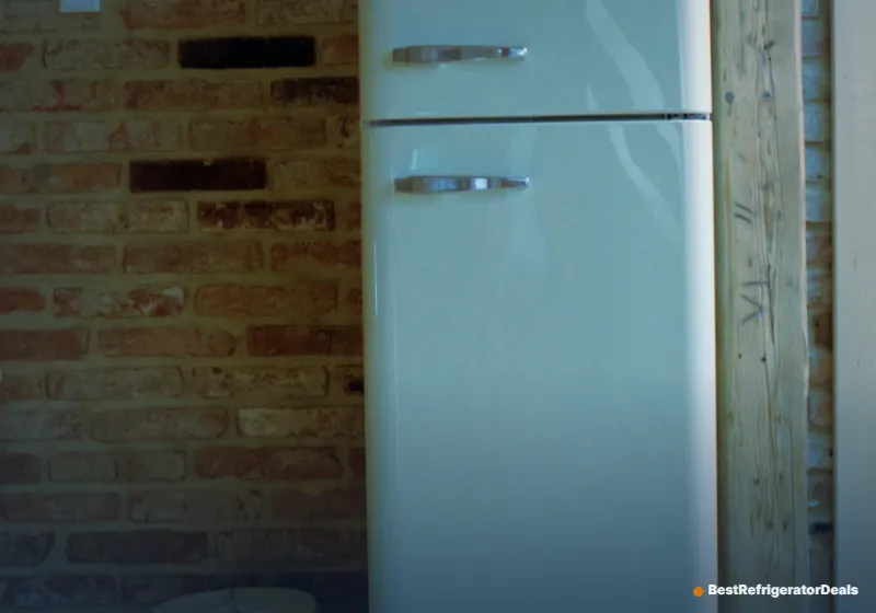 Retro top-freezer refrigerator against a brick wall